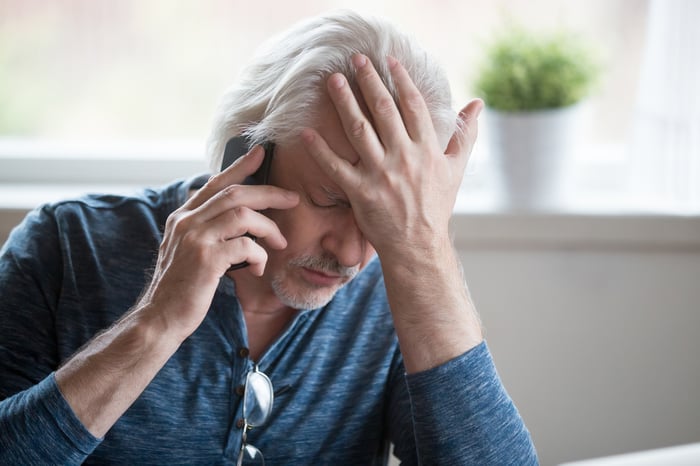 Stressed looking person making a phone call.